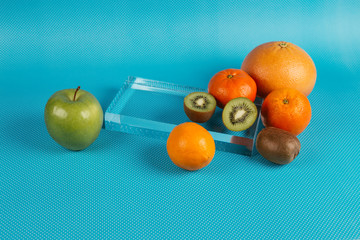 An apple, lemon, orange, tangerine, kiwis and grapefruit photographed on blue background with dots.