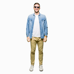 Naklejka premium Handsome man wearing fashion sunglasses with a happy and cool smile on face. Lucky person.