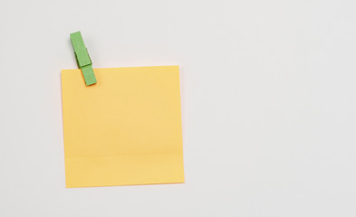 Orange paper notes fastened with a wooden clothespin on a white background.