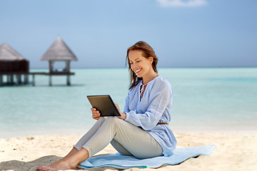 technology, people and leisure concept - happy smiling woman with tablet pc computer over tropical...