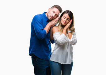 Young couple in love over isolated background sleeping tired dreaming and posing with hands together while smiling with closed eyes.