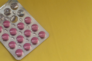 Red round tablets in an open package on a yellow background