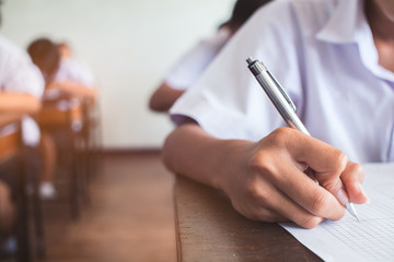 Close up to School student is taking exam and writing answer in classroom for education test concept