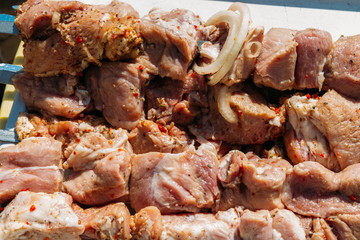 pieces of raw meat on skewers lies on a white tray. barbecue. cook meat with onions and peppers. pickled, picnic, street food