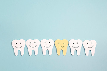 Funny tooth characters, happy healthy teeth and a sick tooth on blue background. Dental health concept.