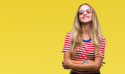 Young beautiful blonde woman wearing sunglasses over isolated background happy face smiling with crossed arms looking at the camera. Positive person.