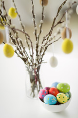 holidays and object concept - close up of pussy willow branches and colored easter eggs in vase on table