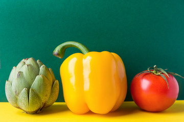 Ripe organic vegetables artichoke capsicum tomato on duotone dark green yellow background. Healthy...