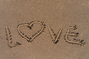 The word Love written in the smooth fine grained beach sand. Summer vacation vibes on a sunny day. 