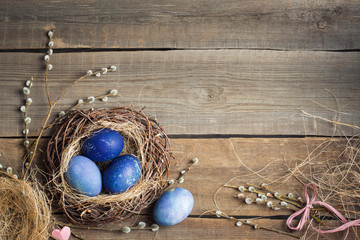 Fototapeta na wymiar Easter background. blue eggs in a nest of straw and willow branches on a wooden table.