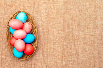 Easter eggs concept, table arrangement decoration. Pink (rosy) and blue eggs in wicker basket on...