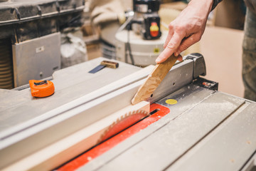 Carpentry workshop - the master saws the wooden bar - safety precautions when working on a circular...
