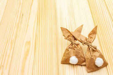 Easter bunny (rabbit) paper gift wrapping idea. Handicraft (homemade) concept for children (kids). On wooden background