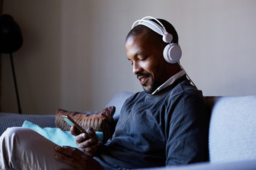 Attractive African American man with headphones listening to music on his phone. Concept of relaxation
