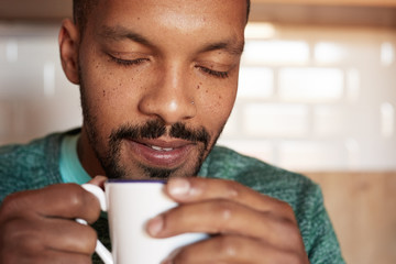 African american black man holding cup of coffee at home. Closeup