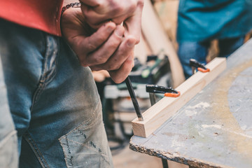 Carpentry workshop - master chisel makes a mounting hole for a spike in a wooden bar