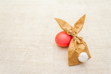 Easter bunny (rabbit) paper gift egg wrapping idea. Handicraft (homemade) concept for children (kids). On vintage cloth (linen) background