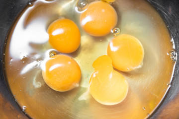 Broken eggs before cooking in a steel bowl