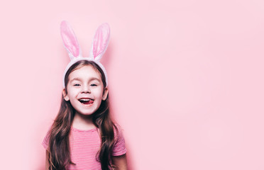 Obraz na płótnie Canvas Cute little girl with bunny ears on pink background. Easter child portrait, funny emotions, surprise. Copyspace for text.