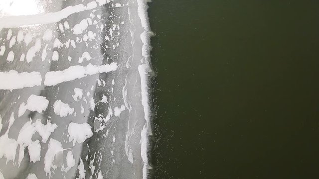 Top view of floating dark water of river covered with ice. Winter landscape. Real time full hd video footage.
