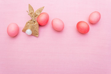 Easter bunny (rabbit) paper gift egg wrapping idea. Handicraft (homemade) concept for children (kids). On pink cloth (linen) background, top view