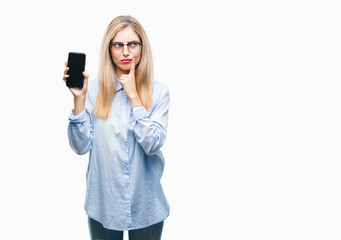 Young beautiful blonde business woman showing screen of smartphone over isolated background serious...