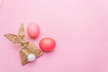 Fototapeta na wymiar Easter bunny (rabbit) paper gift egg wrapping idea. Handicraft (homemade) concept for children (kids). On pink cloth (linen) background