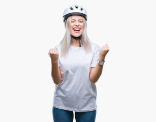 Young blonde woman wearing cyclist security helmet over isolated background celebrating surprised and amazed for success with arms raised and open eyes. Winner concept.
