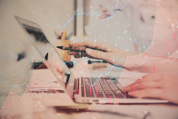 Hands typing on laptop. Business and Financial concept. Double exposure of stock market charts.
