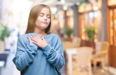 Young beautiful girl wearing winter sweater over isolated background smiling with hands on chest with closed eyes and grateful gesture on face. Health concept.