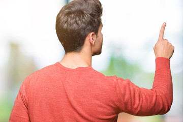 Young handsome man over isolated background Posing backwards pointing behind with finger hand