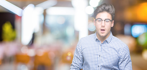 Fototapeta na wymiar Young handsome man wearing glasses over isolated background afraid and shocked with surprise expression, fear and excited face.