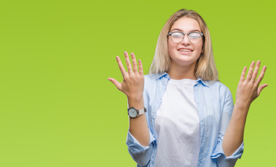 Young caucasian business woman wearing glasses over isolated background celebrating mad and crazy for success with arms raised and closed eyes screaming excited. Winner concept