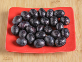 Black grapes on a plate. Drops of water on the grapes.