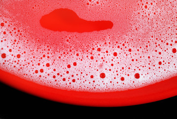 Soap sud on red background. Detergent concept. Foam with bubbles. Shampoo in water. Flat lay.