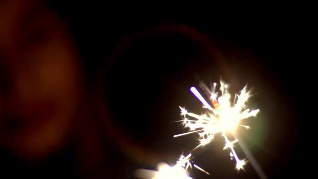 Sparkler sparkles in the dark with many bright ixora and illuminates the silhouette of the girl watching the lights