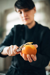 Chef peeling orange in the kitchen