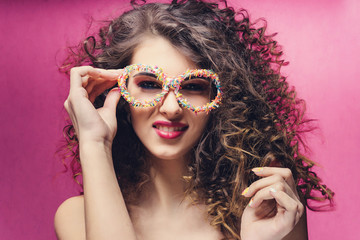 Beautiful girl with colourful manicure smile in confectionery dressing glasses