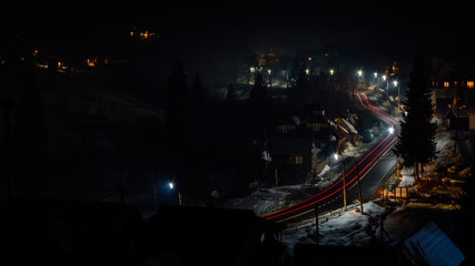 Naklejka premium A wonderful panorama of the night mountain village of Ukraine with car tracks