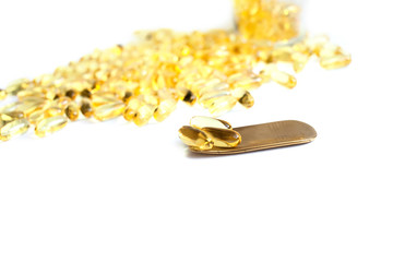 A lot of fish oil omega 3 6 9 capsules on a brass golden spoon. sports nutrition healthy food and lifestyle copy space