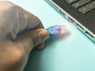 hand plugging in the internet cable to a laptop