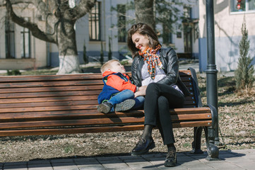 Mom talking to her son. Early spring, Park, bench. A boy with blond hair in a red and blue jacket.  The girl in the black leather jacket. Maternal feeling. Love. Concern. Family.