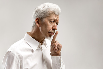 Serious senior frightened male keeps fore finger on lips, tries to keep conspiracy, says: Shh, make...