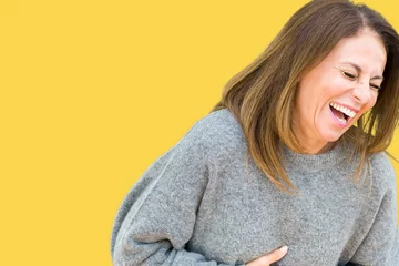 Fotobehang Beautiful middle age woman wearing winter sweater over isolated background Smiling and laughing hard out loud because funny crazy joke. Happy expression. © Krakenimages.com