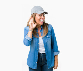 Beautiful middle age woman wearing sport cap over isolated background smiling with hand over ear listening an hearing to rumor or gossip. Deafness concept.
