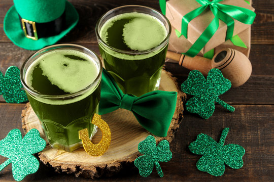 St.Patrick 's Day. celebration. green beer, leprechaun hat, coins, bow tie and clover on a brown background.