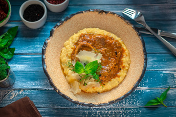 risotto with osso buco on a plate on a blue wooden background, traditional Italian dish, top view