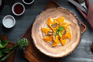 Cooked colored ravioli pasta with pumpkin on a plate, served in the restaurant. Top view