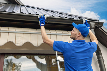 man installing house roof rain gutter system