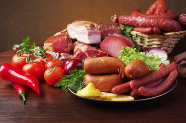 Meat products. Ham, sausage and vegetables on the kitchen board
